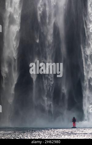 Eine Person steht vor dem riesigen skogafoss im Süden islands. Stockfoto