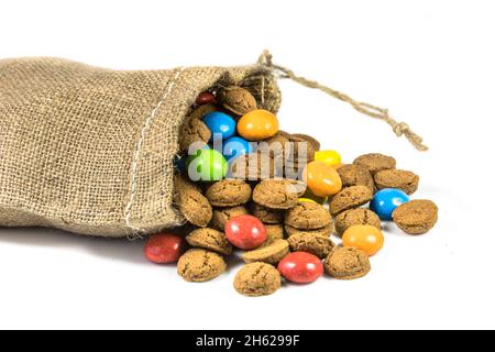 Bunte pepernoten behandelt in Jute Tasche auf weißem Hintergrund für die jährliche Sinterklaas holiday Event in den Niederlanden am 5. Dezember Stockfoto