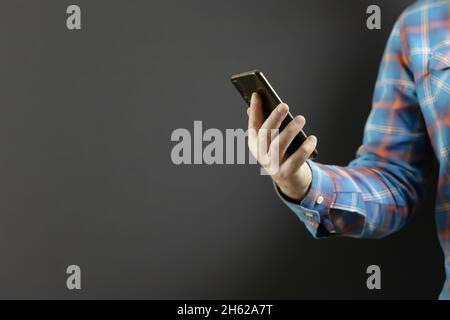 Die Hand des Mannes in einer karierten Hülle hält ein Mobiltelefon Stockfoto