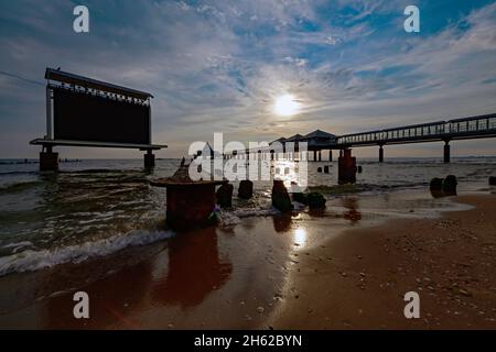 Blick über den Strand mit der gesamten markanten Seebrücke und der Projektionswand, die bei Sonnenaufgang im Wasser am Strand von heringsdorf steht Stockfoto