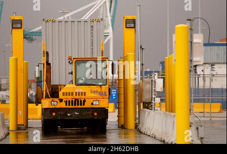 Ein von einem Hafenfahrzeug gezogener Transportcontainer kommt zum Scannen mit auf Lastwagen montierten Strahlungserkennungssystemen an, die von US-Zoll- und Grenzschutzbeamten im Hafen von Miami am 07. Dezember 2015 betrieben werden. Stockfoto
