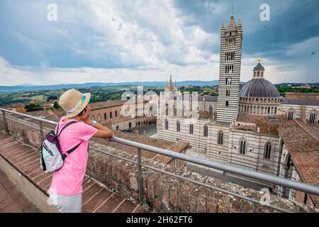 Junger Tourist, 10 Jahre alt, beobachtet von oben die Kathedrale santa maria assunta, siena, toskana, italien Stockfoto