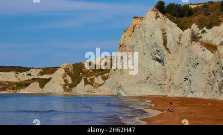 griechenland, griechische Inseln, ionische Inseln, kefalonia, xi-Strand, roter Sand, weiß, himmelblau, eine Frau sitzt allein am Strand Stockfoto