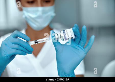 COVID-19-Impfstoff in Forscherhand hält Ärztin Spritze und Flasche mit Impfstoff für die Coronavirus-Heilung. Stockfoto