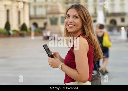 Ehrliche nachdenkliche Mädchen hält Handy für den Online-E-Commerce im Freien einkaufen. Speicherplatz kopieren. Stockfoto