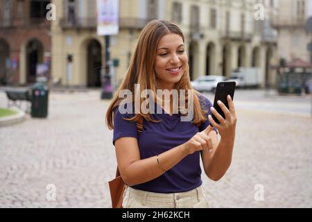 Attraktive junge Frau, die mit dem Mobiltelefon auf der Stadtstraße läuft Stockfoto
