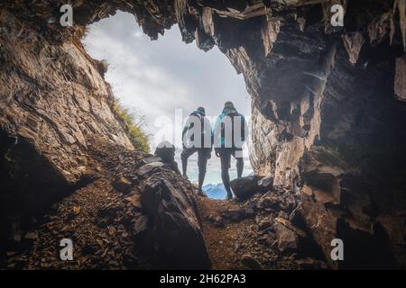 Zwei Wanderer im Hintergrund am Eingang zu einer Höhle in den Bergen,col di lana,dolomites,livinallongo del col di lana,belluno,veneto,italien Stockfoto