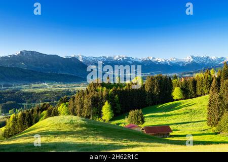 Frühling im allgäu. Blick über das illertal auf die allgäuer alpen mit den grünten. Wiesen, Wälder und schneebedeckte Berge unter blauem Himmel. bayern, deutschland, europa Stockfoto