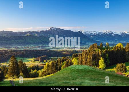 Frühling im allgäu. Blick über das illertal auf die allgäuer alpen mit den grünten. Wiesen, Wälder und schneebedeckte Berge unter blauem Himmel. bayern, deutschland, europa Stockfoto