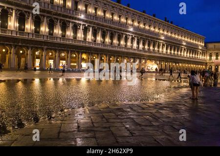 Fantastische Nacht auf dem markusplatz mit dem campanile und der Basilika des heiligen Markus. Bunte abendliche Stadtansicht von venedig, italien, europa mit viel reflektierendem Wasser. Stockfoto