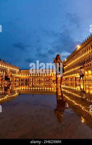 Fantastische Nacht auf dem markusplatz mit dem campanile und der Basilika des heiligen Markus. Bunte abendliche Stadtansicht von venedig, italien, europa mit viel reflektierendem Wasser. Stockfoto