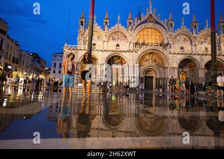 Fantastische Nacht auf dem markusplatz mit dem campanile und der Basilika des heiligen Markus. Bunte abendliche Stadtansicht von venedig, italien, europa mit viel reflektierendem Wasser. Stockfoto