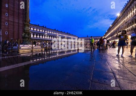 Fantastische Nacht auf dem markusplatz mit dem campanile und der Basilika des heiligen Markus. Bunte abendliche Stadtansicht von venedig, italien, europa mit viel reflektierendem Wasser. Stockfoto