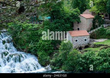 Wasserfall und historisches Dorf mit alten Häusern im nationalpark krka in kroatien, europa Stockfoto