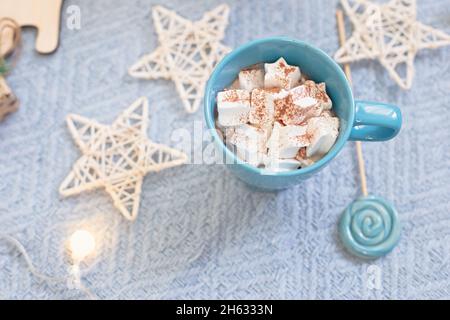 Blauer Becher mit Kakaomarmelibe, blauer Lollipop vor dem Hintergrund des Weihnachtsdekor Stockfoto