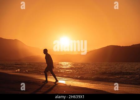 Menschen am Strand in Bewegung bei Sonnenuntergang Stockfoto