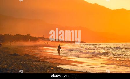 Menschen am Strand in Bewegung bei Sonnenuntergang Stockfoto