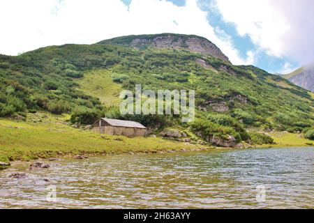 Wanderung zum Zreiner See auf 4 Hektar Bergsee auf 1799 m in den brandenberger alpen,tirol,gemeinde münster,alte Steinmauer-Almhütte mit Schindeldach,im Hintergrund der Latschberg (1949 m) Stockfoto