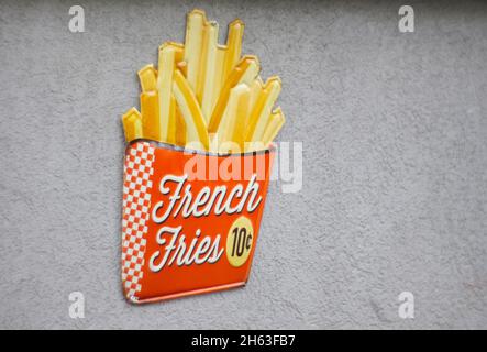 Emaille-Werbeschild für pommes Frites an einer Hauswand. Stockfoto