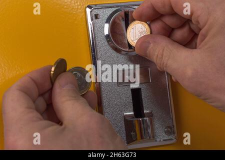 Nahaufnahme des Mannes, der eine Euro-Münze auf den Spielautomaten wirft. Schweden. Stockfoto