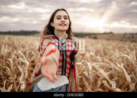 Eine lateinische Frau, die sich zur Kamera streut und zu einer Reise einlädt. Kommen Sie mit mir. Stockfoto