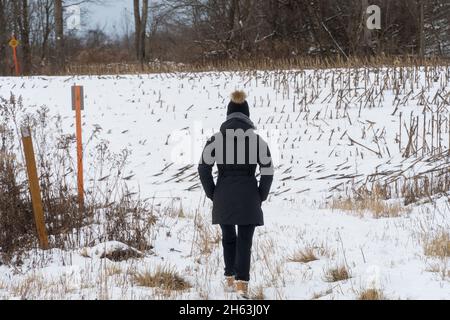 Frau in Schneekleidung geht draußen im Winterfeld Stockfoto