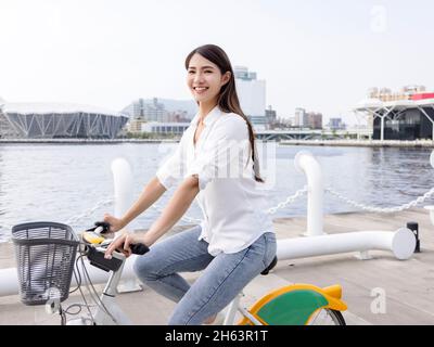 Junge Frau, die im Stadtpark Fahrrad fährt Stockfoto