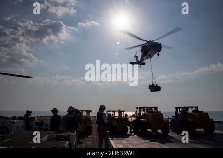 GOLF VON OMAN (NOV 11, 2021) Seefahrer und Marineinfanteristen führen auf dem Flugdeck des amphibischen Angriffsschiffs USS Essex (LHD 2) mit dem Trocken- und Munitionsschiff USNS Cesar Chavez (T-AKE 14), November 11, eine vertikale Nachfüllung auf See durch. Essex und die 11. Marine Expeditionary Unit werden im Einsatzgebiet der 5. US-Flotte eingesetzt, um Marineoperationen zu unterstützen, um die maritime Stabilität und Sicherheit in der Zentralregion zu gewährleisten und das Mittelmeer und den Pazifik durch den westlichen Indischen Ozean und drei strategische Engpässe zu verbinden. (USA Navy Foto von Mass Communication Specialist 2nd Clas Stockfoto