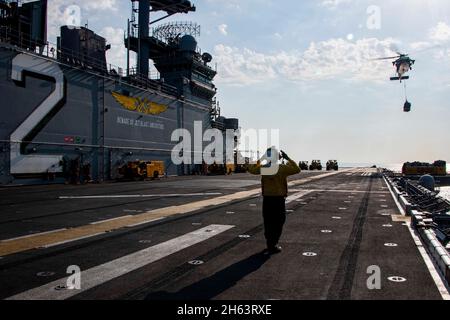 GOLF VON OMAN (NOV 11, 2021) Aviation Boatswain's Mate (Handling) 2nd Class Dominique Simmons signalisiert einem MH-60S Sea Hawk Hubschrauber, der an das Hubschrauber Sea Combat Squadron 21 an Bord des amphibischen Sturmschiffs USS Essex (LHD 2) während einer vertikalen Nachfüllung auf See mit dem Trockenfracht- und Munitionsschiff USNS Cesar Chavez (T-AKE 14) angebracht ist, Nov. 11. Essex und die 11. Marine Expeditionary Unit werden im Einsatzgebiet der 5. US-Flotte eingesetzt, um Marineinteroperationen zu unterstützen, um die maritime Stabilität und Sicherheit in der Zentralregion zu gewährleisten und das Mittelmeer und den Pazifik durch t zu verbinden Stockfoto