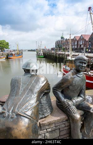 deutschland, niedersachsen, ostfriesland, neuharlingersiel im Fischereihafen. Alte und junge Fischer vom Bildhauer hans-christian petersen. Stockfoto