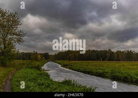 deutschland,luckenwalde,21. oktober 2021,Sturm 'hendrik',viele Wolken am Himmel über einer Wiese mit einem Fluss während des Sturms Stockfoto