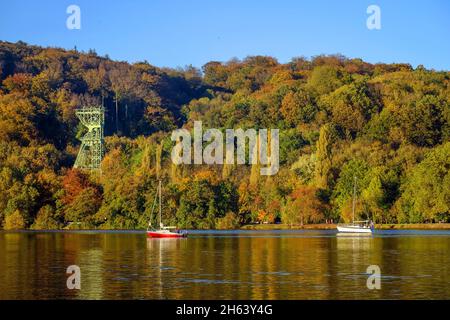 essen, Nordrhein-westfalen, deutschland - Goldener Herbst am baldeney-See. Segelboote vor dem Förderrahmen der ehemaligen carl funke-Kolonie. Die carl funke-Kolonie war ein Kohlebergwerk in essen-heisingen am Nordufer des baldeney-Sees. Stockfoto