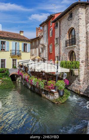 Restaurant Terrasse mit Blumen auf dem fluss mincio, borghetto, Bezirk valeggio sul mincio, Mühlendorf, Po-Tal, provinz verona, venetien, italien Stockfoto