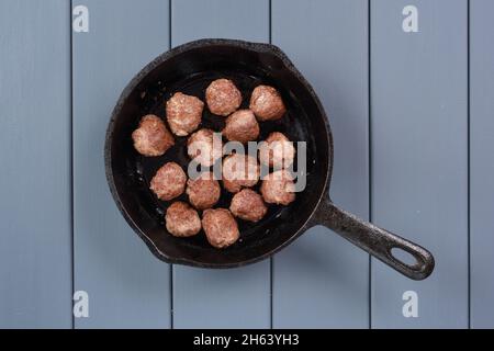 Kleine hausgemachte unperfekte Fleischbällchen in gusseiserner Pfanne auf grauem Hintergrund Draufsicht Stockfoto