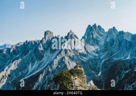 Luftaufnahme eines Mannes mit erhobenen Händen, der die Berggipfel von cadini di misurina, die italienischen alpen, die dolomiten, italien, europa genießt. Stockfoto