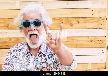 Verrückte nette alte ältere Mann Ausdruck Porträt mit bunten Kleidern - Konzept der Rebellen keine Grenze Alter und Jugendliche Menschen - kaukasischen älteren Mann mit weißem Bart und Haare Rock'n Roll Zeichen Stockfoto