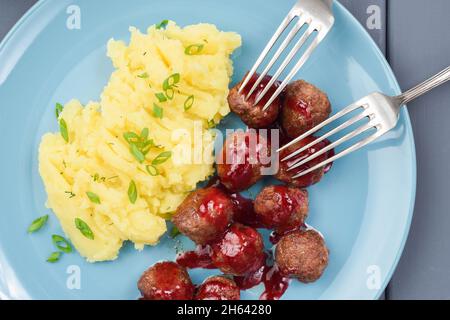 Traditionelles schwedisches Gericht, Fleischbällchen mit Beerensauce und Kartoffelpüree auf blauem Teller oben Stockfoto