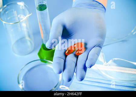 Die Hand des Arztes in einem Handschuh enthält Omega-3-Vitamine. Fischöl. Medizinisches Konzept. Stockfoto