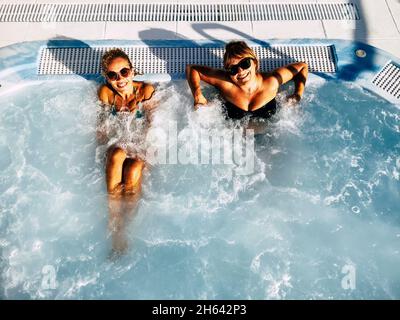 Zwei Freundinnen genießen Sommerferien im Resort und entspannen im Pool Stockfoto