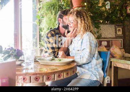 Erwachsene junge kaukasische Paar in Liebe und Zärtlichkeit Emotionen sitzen zusammen im Restaurant genießen Beziehung - Dating reifen Menschen küssen und Spaß beim Mittagessen an der Bar
