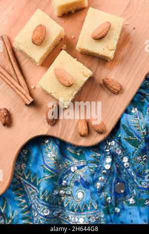 Traditionelles indisches Dessert, Halva aus Mehl und Milch mit Zimt und Mandeln, serviert auf besticktem blauen Tuch von der Decke Stockfoto