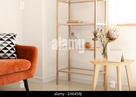 Vase mit getrockneten Blumen und Notizbuch auf dem Tisch im hellen Raum Stockfoto