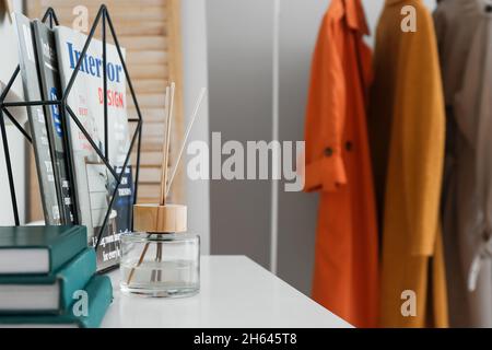 Reed-Diffusor, Notizbücher und Zeitschriften auf weißem Regal im Flur Stockfoto