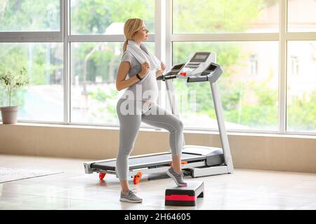 Junge Schwangeren trainieren mit Aerobic Stepper im Fitnessstudio Stockfoto