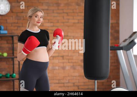 Junge Schwangerin im Fitnessstudio mit Boxhandschuhen Stockfoto