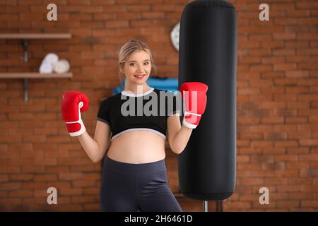 Junge Schwangerin im Fitnessstudio mit Boxhandschuhen Stockfoto