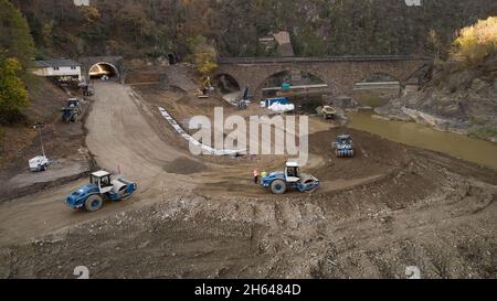 Altenahr, Deutschland. November 2021. Bauarbeiter nutzen schwere Geräte, um die beschädigte Zufahrtsstraße zum Tunnel auf der Bundesstraße 267 bei Altenahr zu reparieren (Luftaufnahme mit einer Drohne). Auch die Überschwemmungen im Ahrtal haben das Straßennetz verwüstet. Nach der Herstellung von provisorischen Lösungen wollen Experten es nun winterfest machen. (To dpa 'temporäre Straßen im Ahr-Hochwassergebiet werden überwintert') Quelle: Thomas Frey/dpa/Alamy Live News Stockfoto