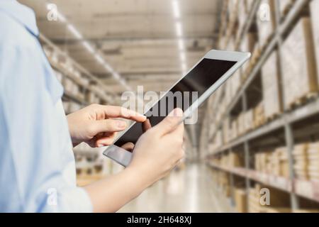 Mitarbeiter, die ein Tablet mit intelligentem Lagerverwaltungssystem einsetzen, verfolgen die Bestandsverwaltung und überwachen das Kontrolllogistiksystem. Stockfoto