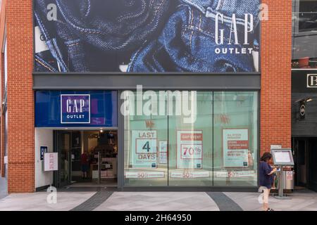 High Wycombe, England - 21. Juli 2021: Eine Frau überprüft ihr Telefon vor einem GAP-Store. Alle Gap Stores haben geschlossen. Stockfoto