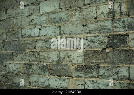 Die Struktur des Mauerwerks der Wand des Gebäudes besteht aus grobem grauen Stein. Uralte Stadtarchitektur. Moosige, feuchte Steine. Außenaufnahmen Stockfoto